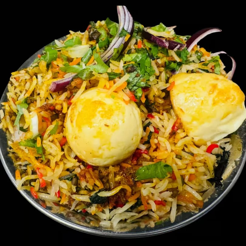 Egg Biryani, an Indian rice dish with two whole boiled eggs, herbs, and spices.